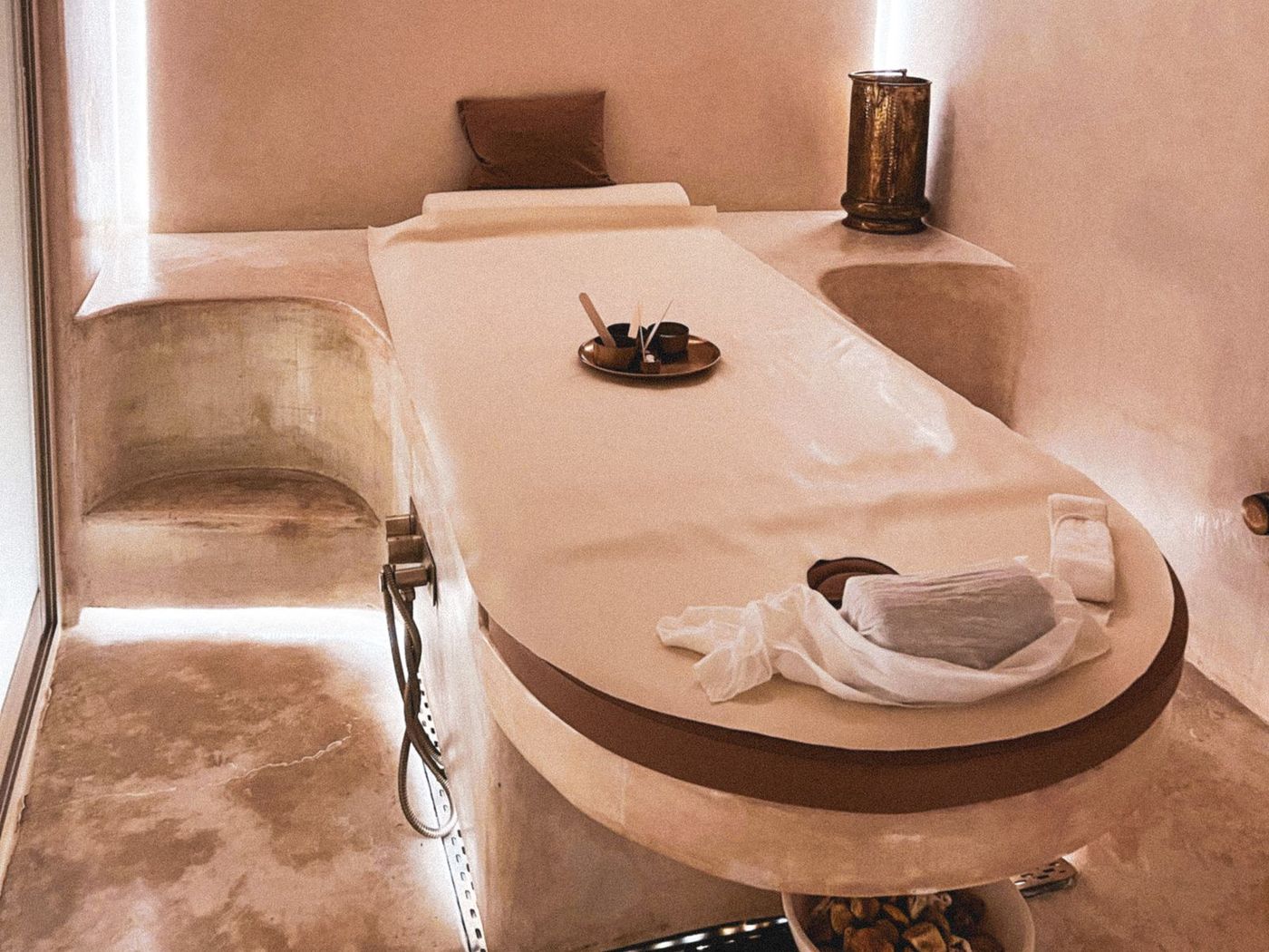 A softly lit treatment room with an arched plaster ceiling and a curved cream treatment table